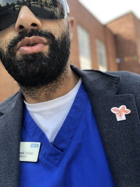 Mo Sattar wearing a root out racism badge