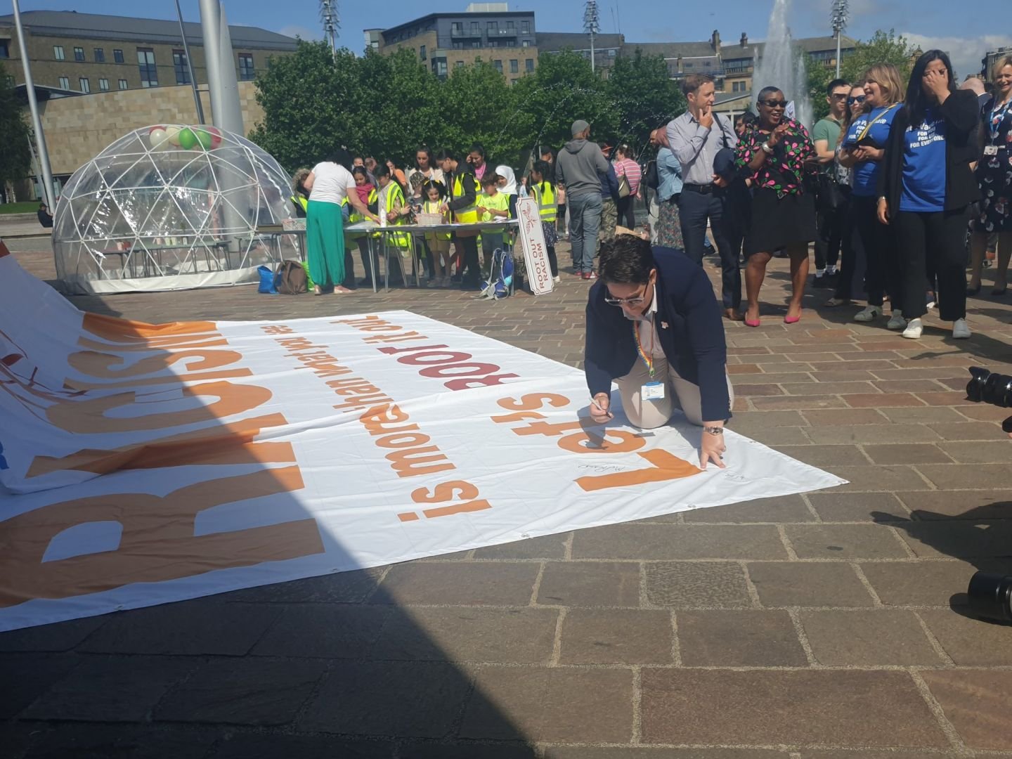 Mel Pickup signing the Root out racism banner at the launch event in Centenary Square