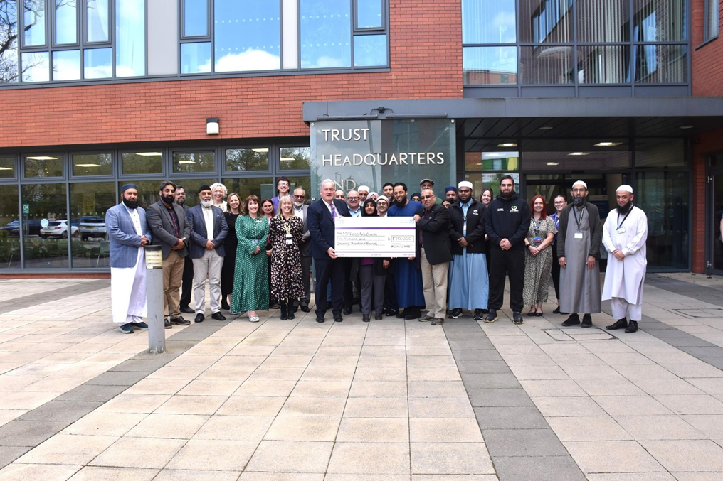 Image of people smiling in front of building with large cheque