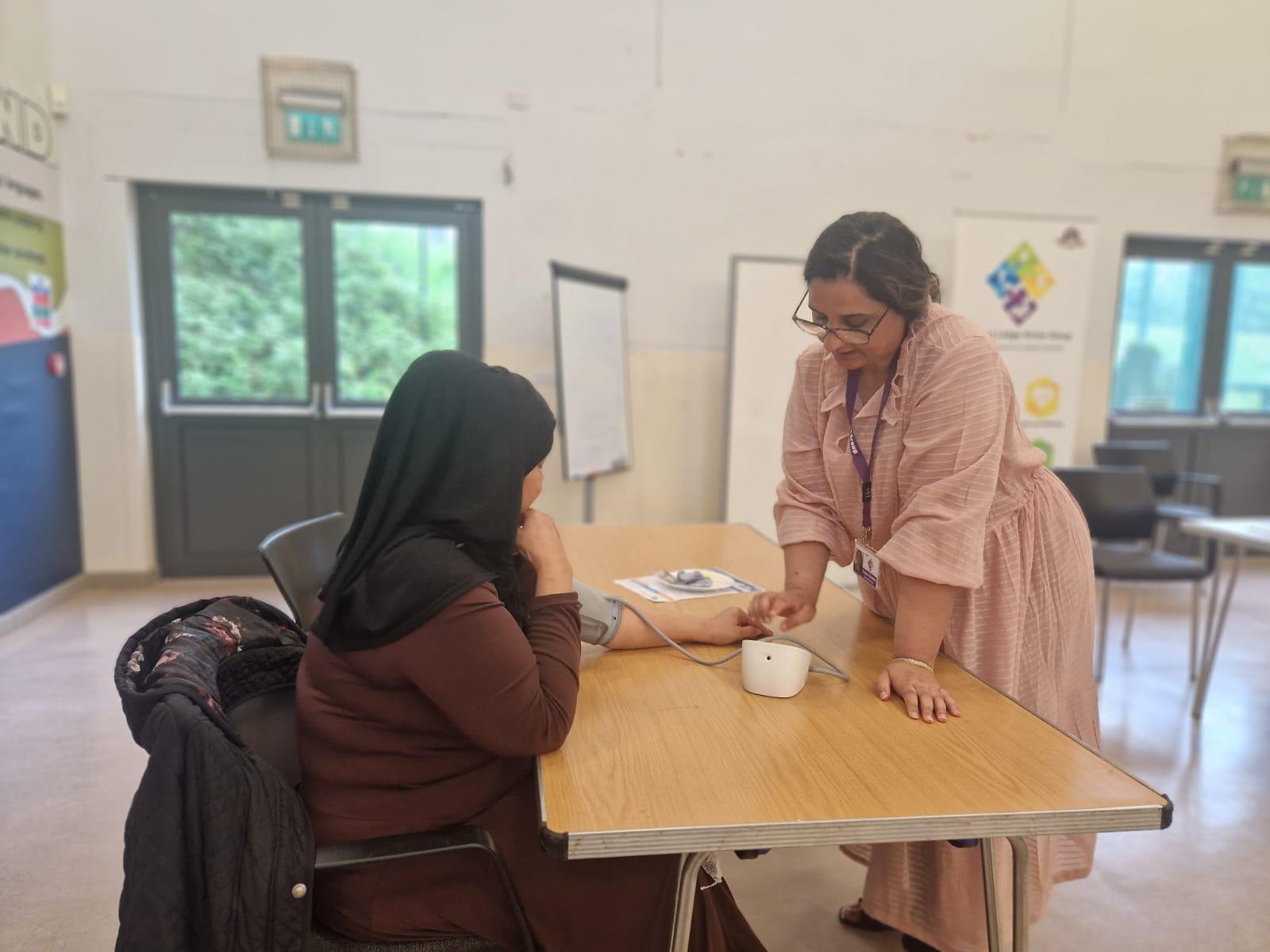 A community champion taking someone's blood pressure