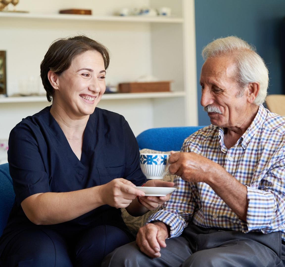 A carer drinking tea with an elderly man