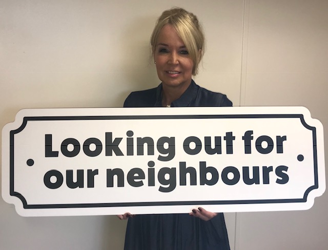 Karen Coleman with a looking out for our neighbours campaign sign