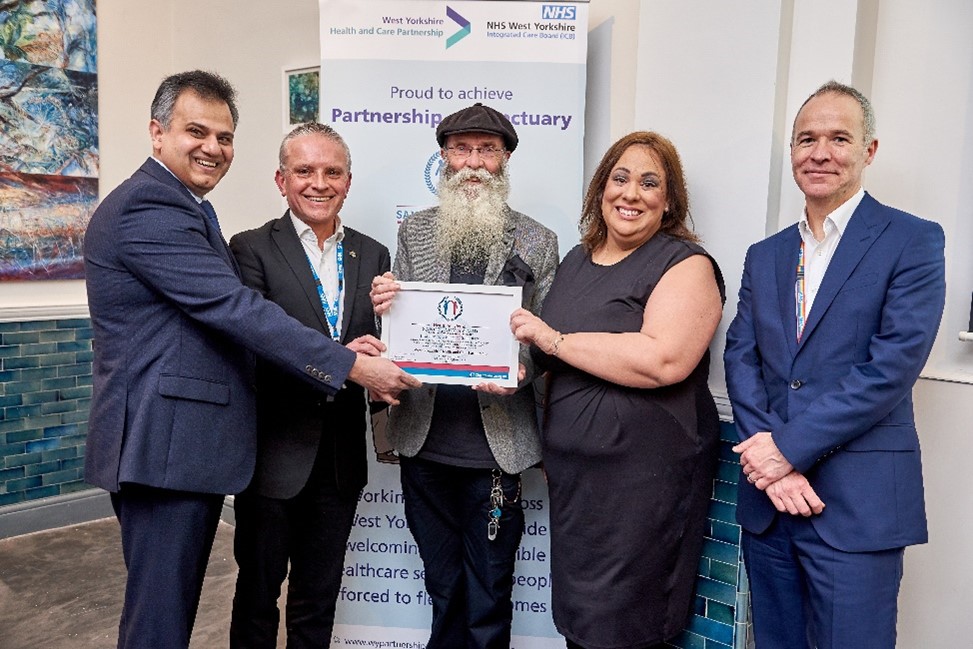 Jeff Morgan (City of Sanctuary) in the centre presenting the certificate to Dr Sohail Abbas (far left) and Robin Tuddenham (second left), Rob Webster (last on the right) and Paula Sherriff )second on the right)