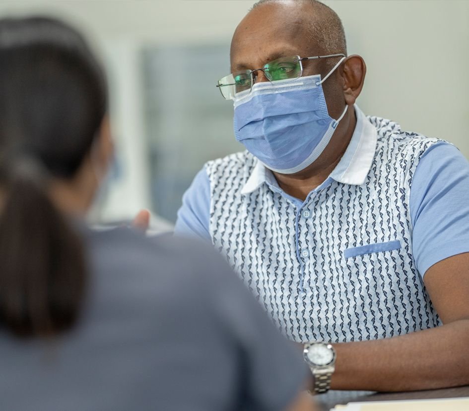 Older Asian man wearing a face mask at a hospital consultation.