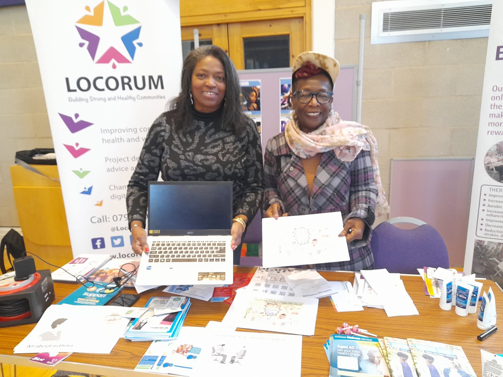 Two community champions at a stall with leaflets and other health material