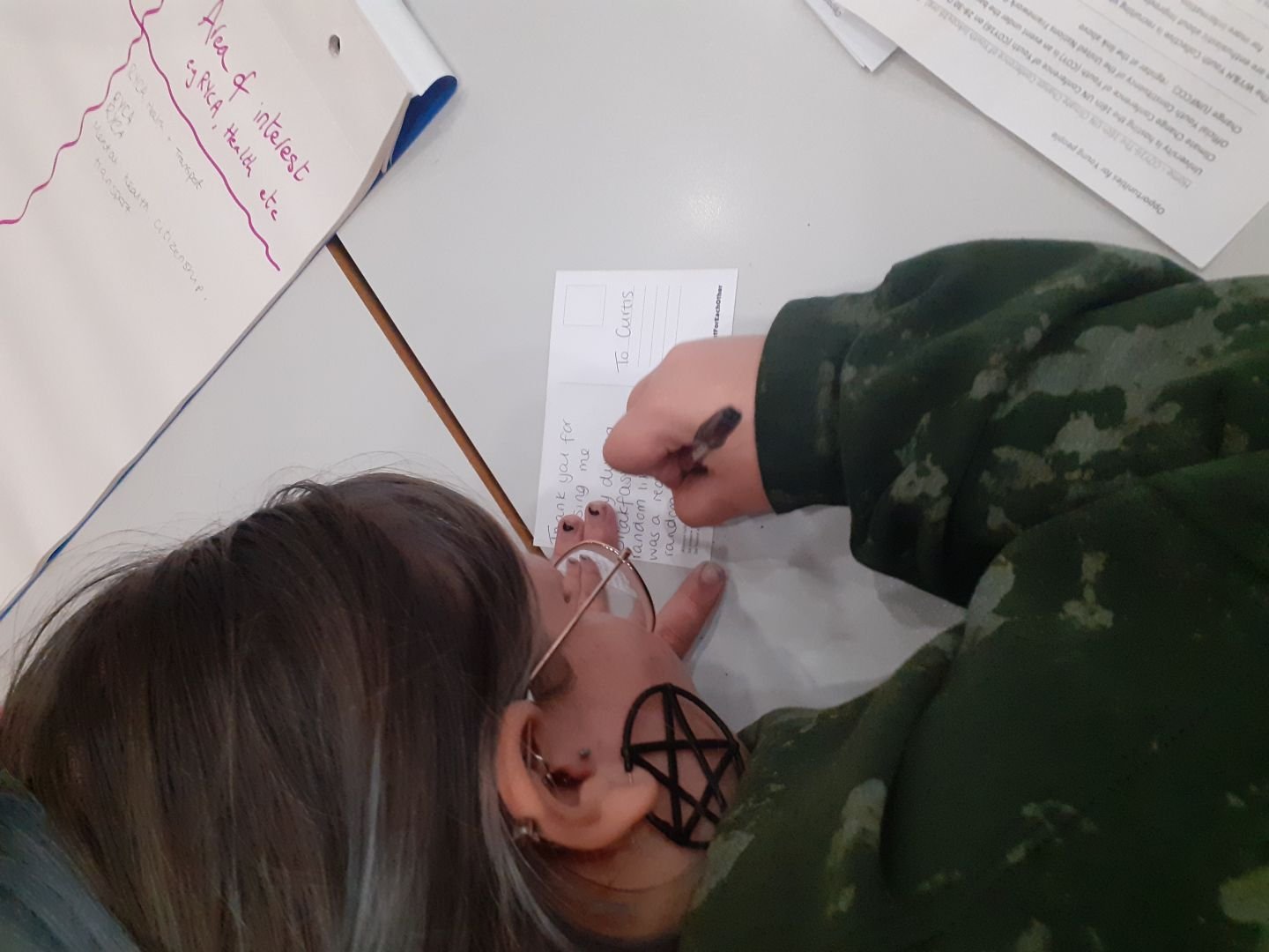 Young person writing a postcard