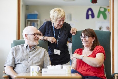 A carer with a man and a woman seated