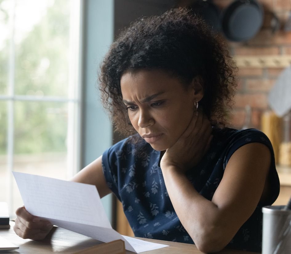 Photo of a young Black woman reading a letter and looking concerned.