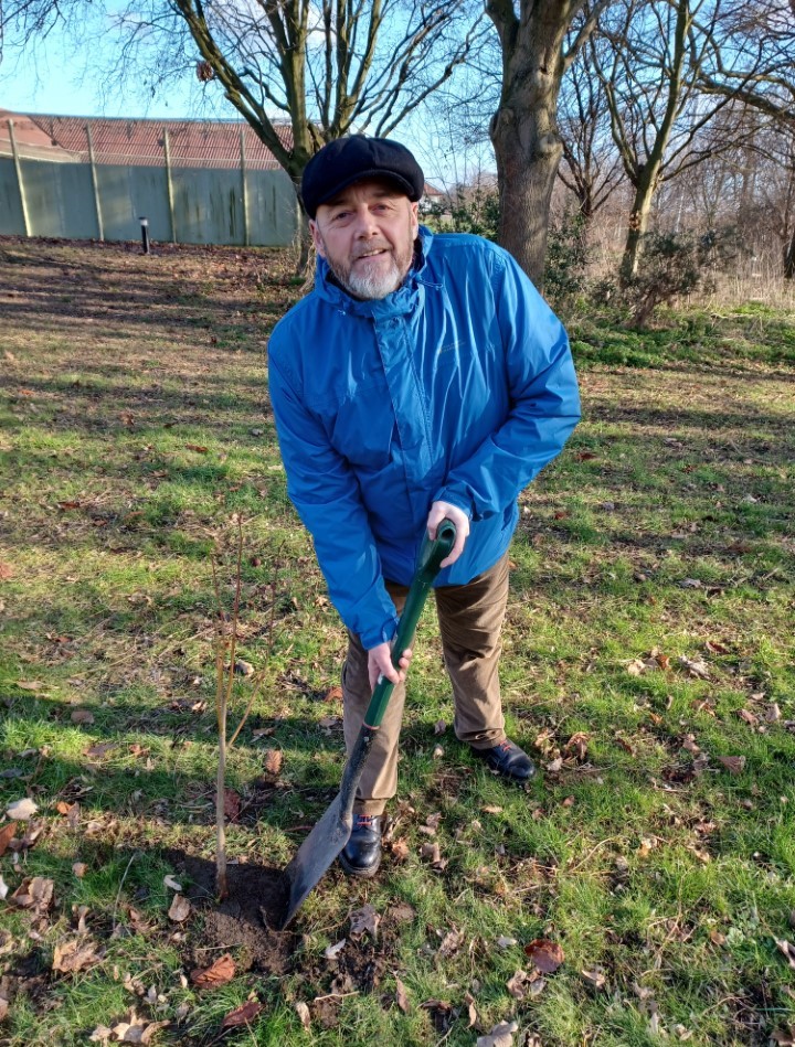 A man wearing a blue jacket and using a spade