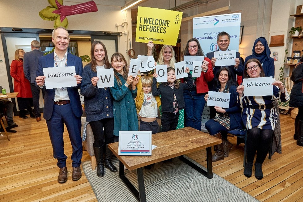 Attendees at an event hold up welcome signs