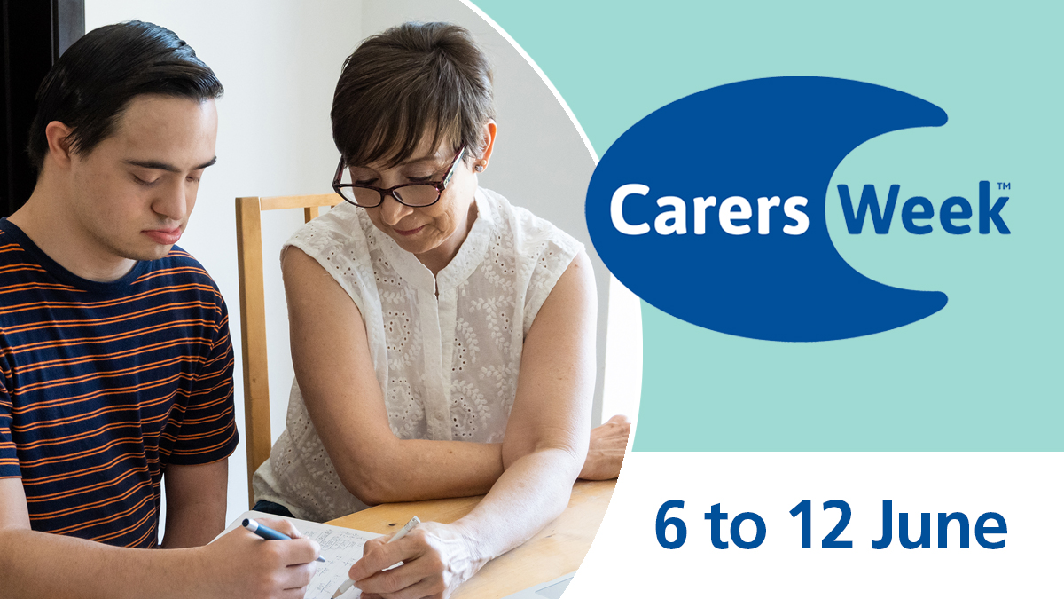 Photograph of a young man who has learning difficulties. He is studying and is being helped by his carer.