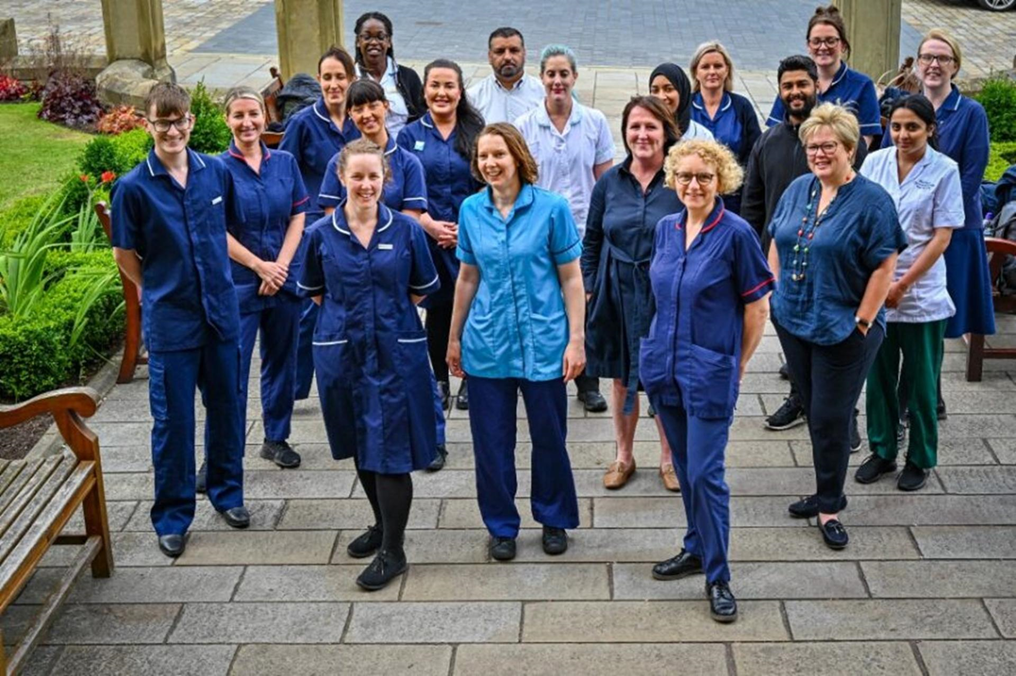 Image of many men and women in healthcare uniforms smiling