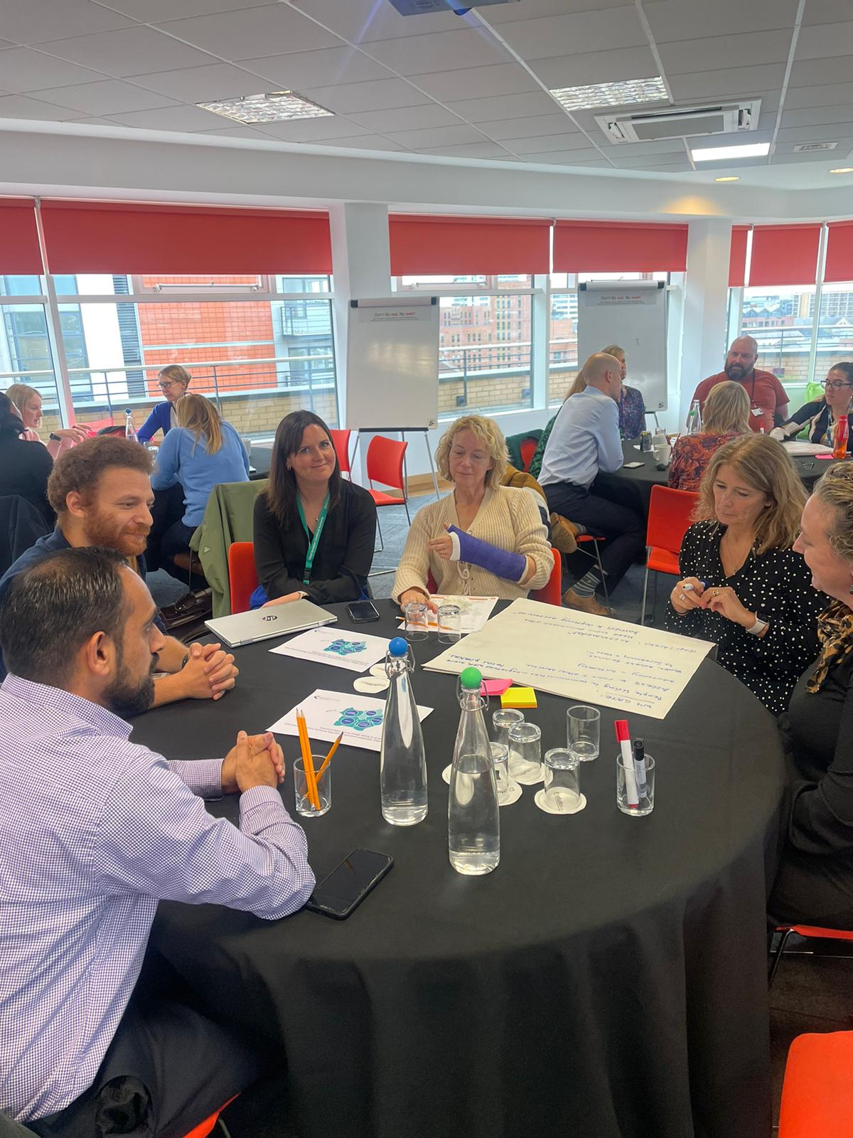 A group of attendees at the inclusion health workshop sat at a table