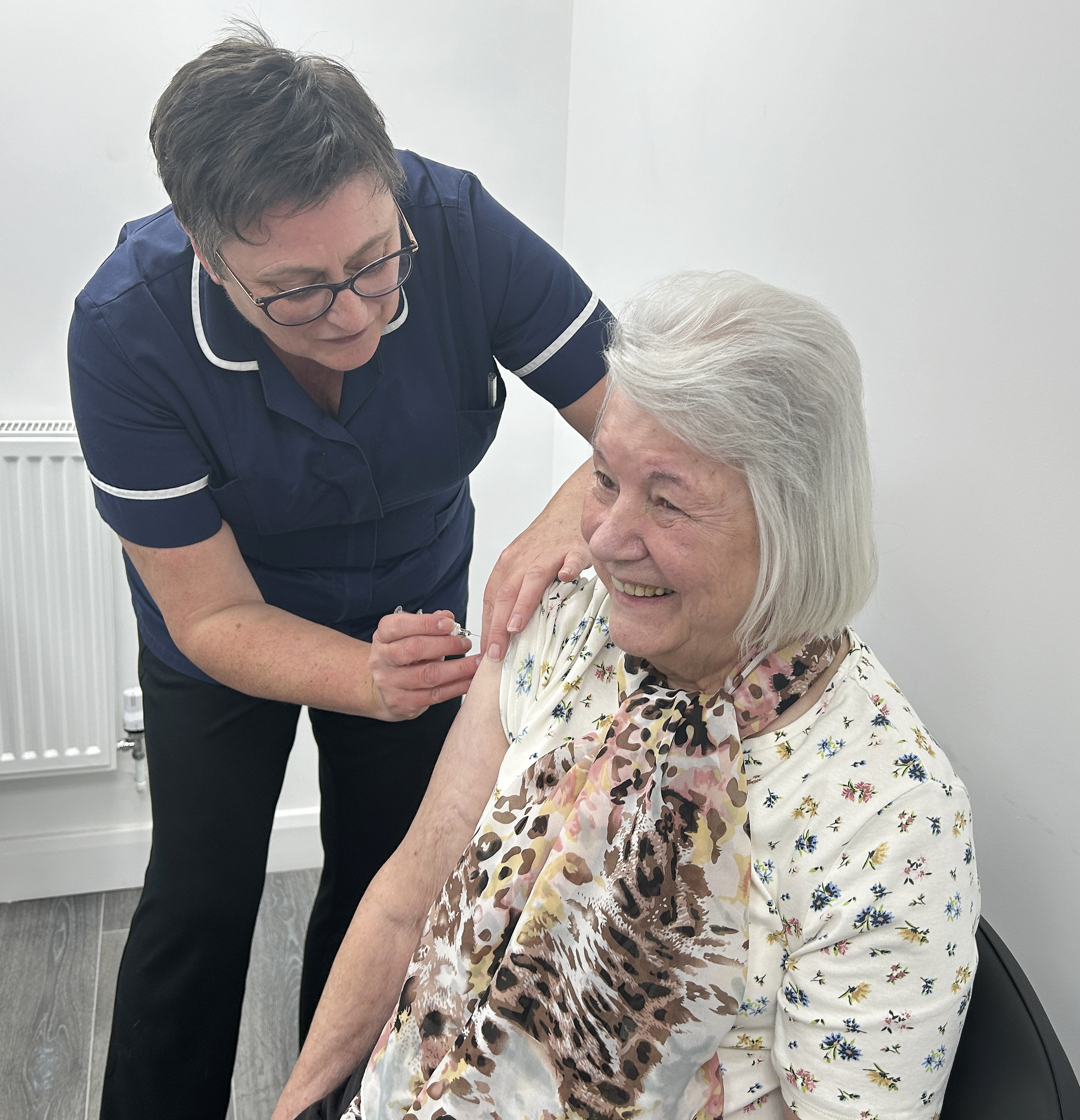 Woman being vaccinated by a healthcare worker who has clean hands and is not wearing disposable gloves.